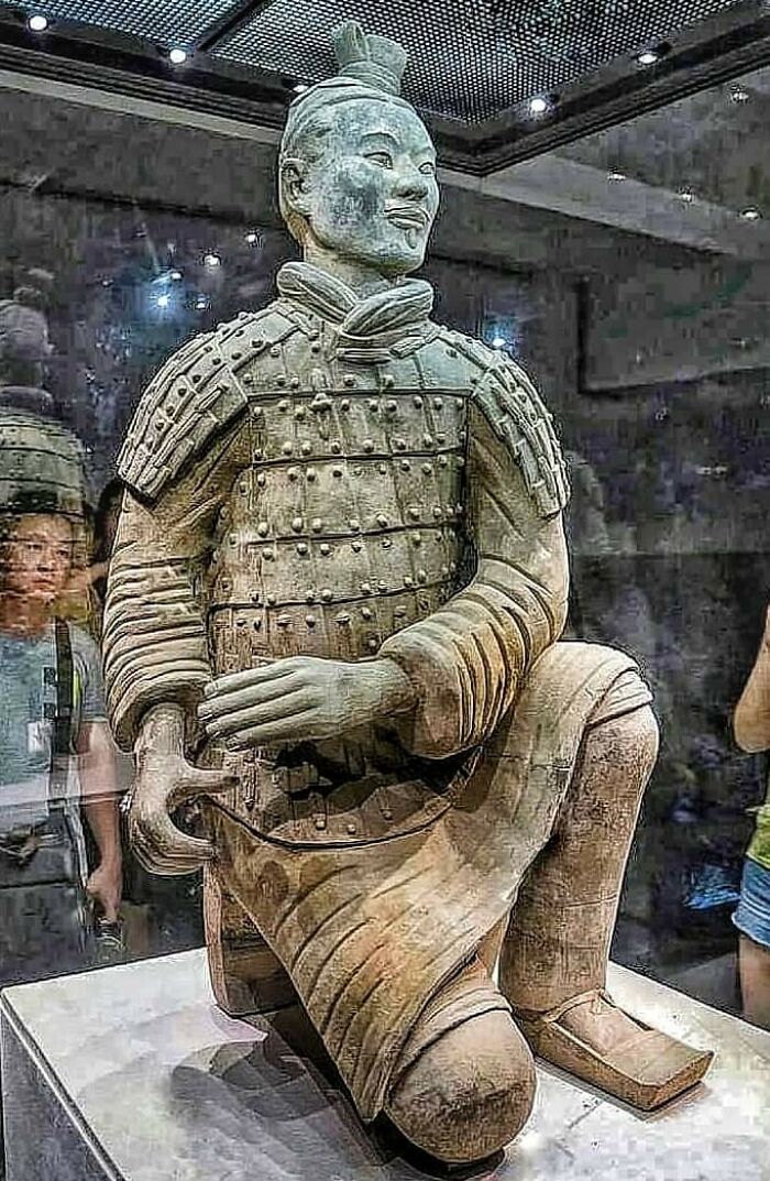 Terracotta warrior statue displayed in museum with visitors, one of the fascinating archeology finds from around the world.
