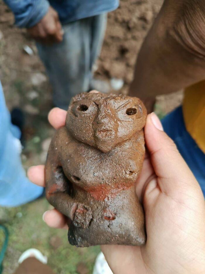 Hand holding an ancient artifact resembling a humanoid figure, one of 107 fascinating archeology finds worldwide.
