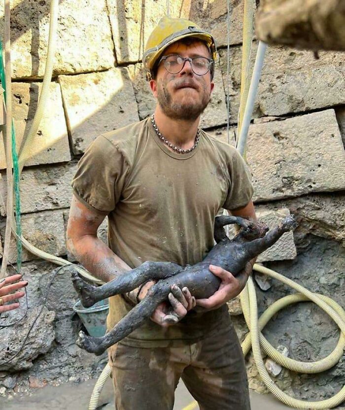 Archeology expert holding a well-preserved ancient bronze statue uncovered at a historic excavation site.