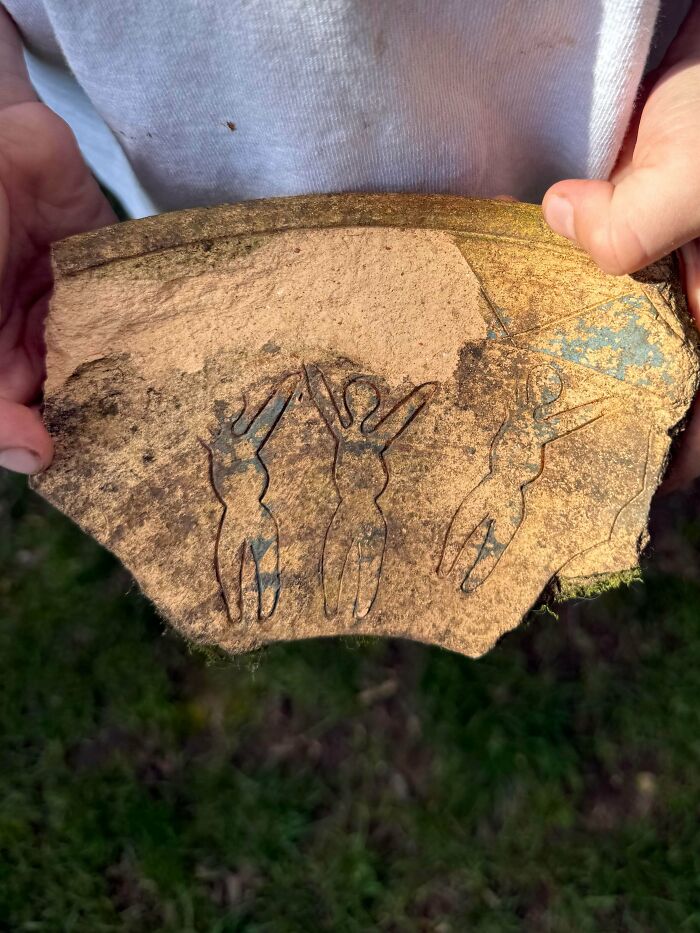 Hands holding an ancient pottery shard with carved figures, one of many fascinating archeology finds worldwide.