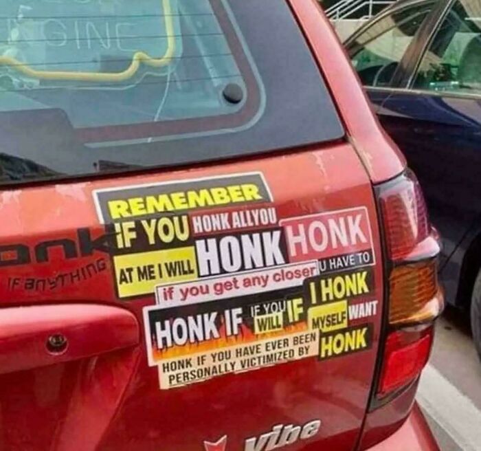 Red car covered in confusing and excessive honk warning stickers, a clear example of failed attempts to make cars cooler.