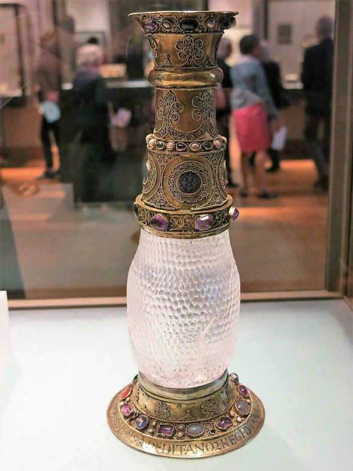 Ornate ancient artifact with intricate gold designs and gemstones, displayed in a museum archaeology exhibit.