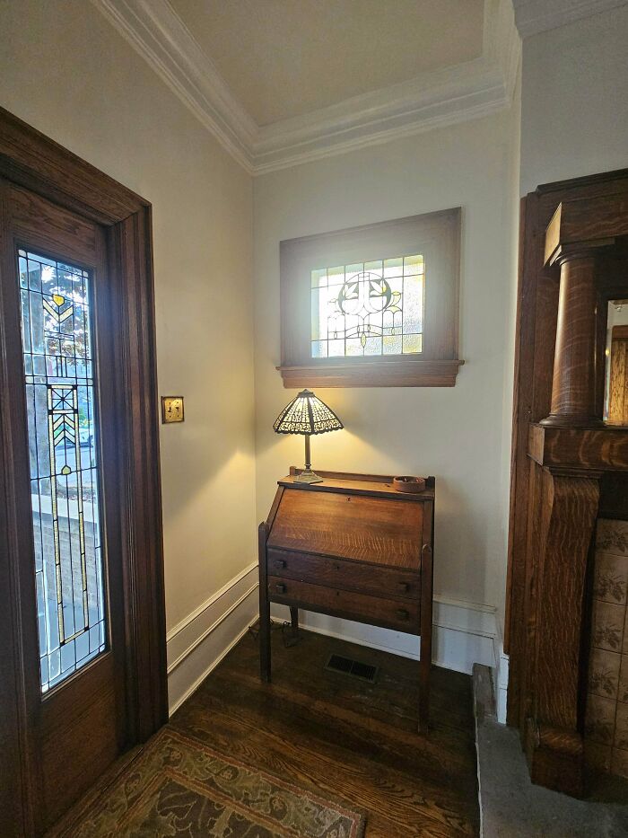 Cozy corner in a beautiful old house featuring vintage wooden furniture and stained glass windows showing craftsmanship.