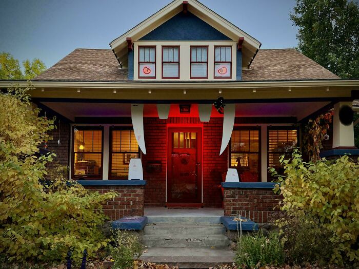 Old house with classic craftsmanship featuring brick walls, wooden windows, and a welcoming porch surrounded by greenery.