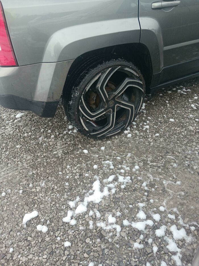 Car with an unusual wheel design on a snowy gravel surface, showing a failed attempt to make the car cooler.