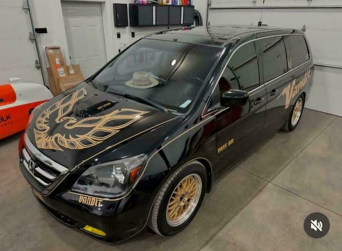 Black minivan customized with gold Pontiac Firebird decal and gold wheels, an example of people trying to make cars cooler.