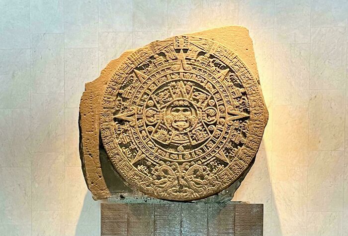 Ancient carved stone artifact with intricate circular designs, a fascinating archeology find displayed in a museum setting.