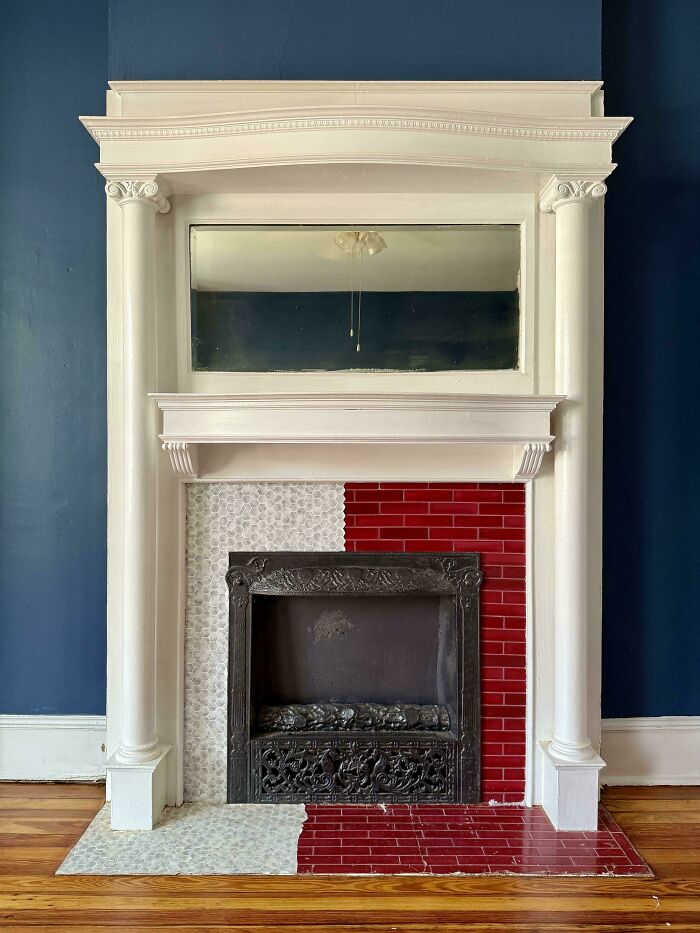Ornate fireplace in a beautiful old house featuring detailed white woodwork and contrasting red and white tile craftsmanship.