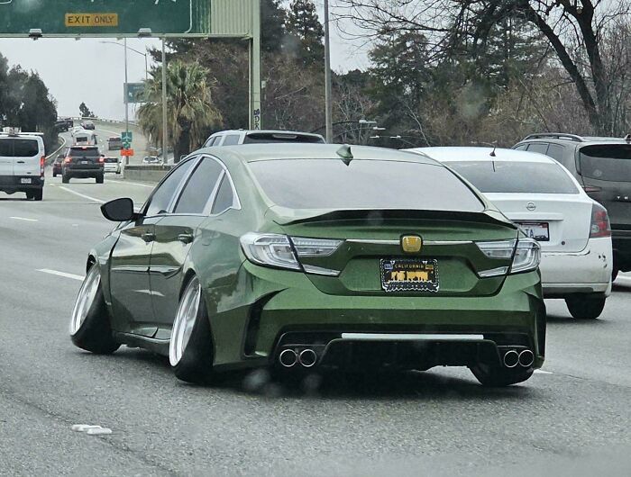 Green modified car with extreme camber wheels on a highway, showcasing a failed attempt to make a car cooler.