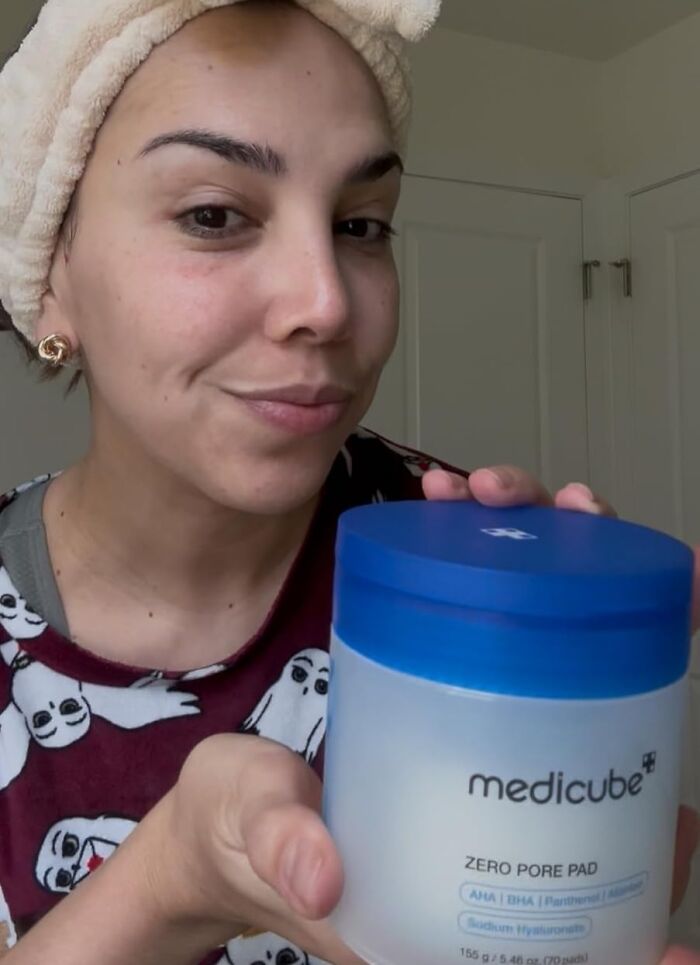 Woman with towel headband holding Medicube skincare product promoting holy grail beauty deals for Black Friday restocking.