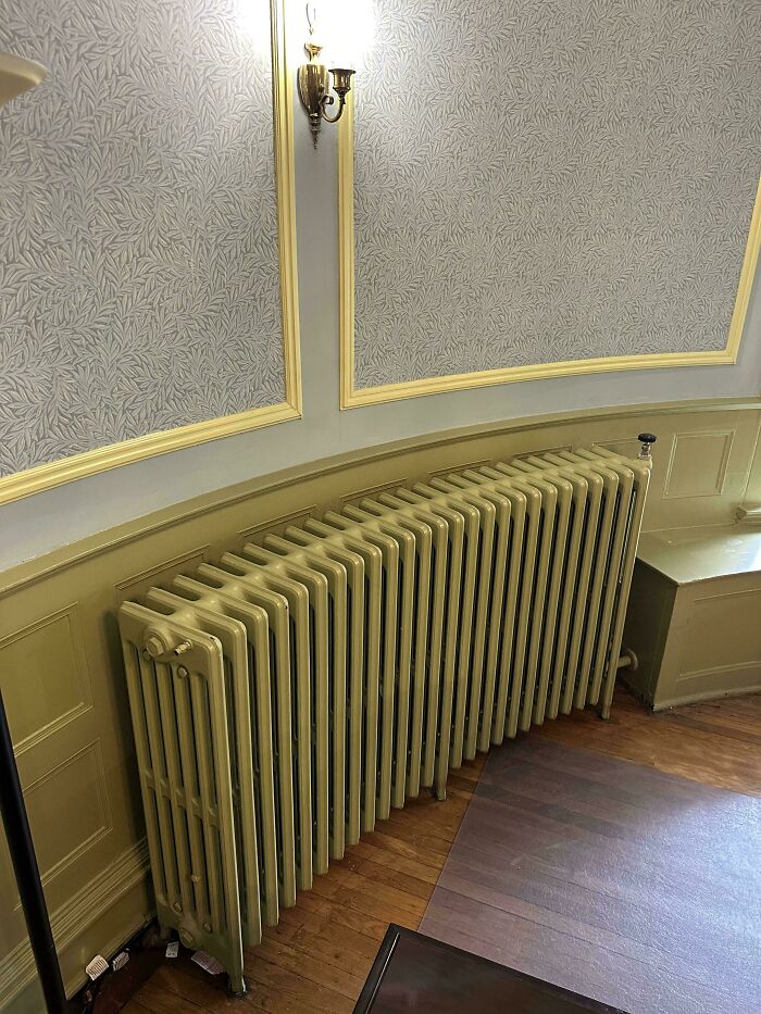 Vintage radiator under detailed molding and wallpaper in a beautiful old house showcasing craftsmanship that stands the test of time