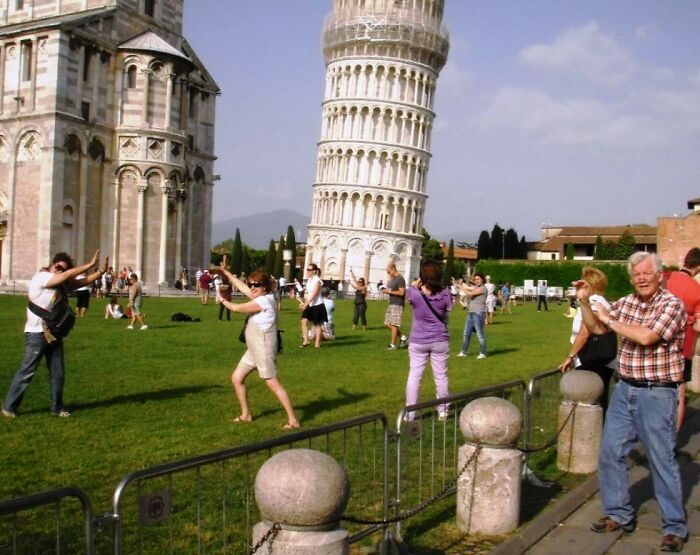 Tourists posing and taking photos around the Leaning Tower of Pisa, illustrating travel destinations beyond Miami hype.
