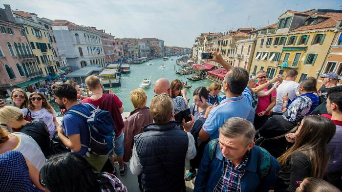 Crowded tourist group overlooking a canal with historic buildings, illustrating Miami as a city that may not meet online hype.