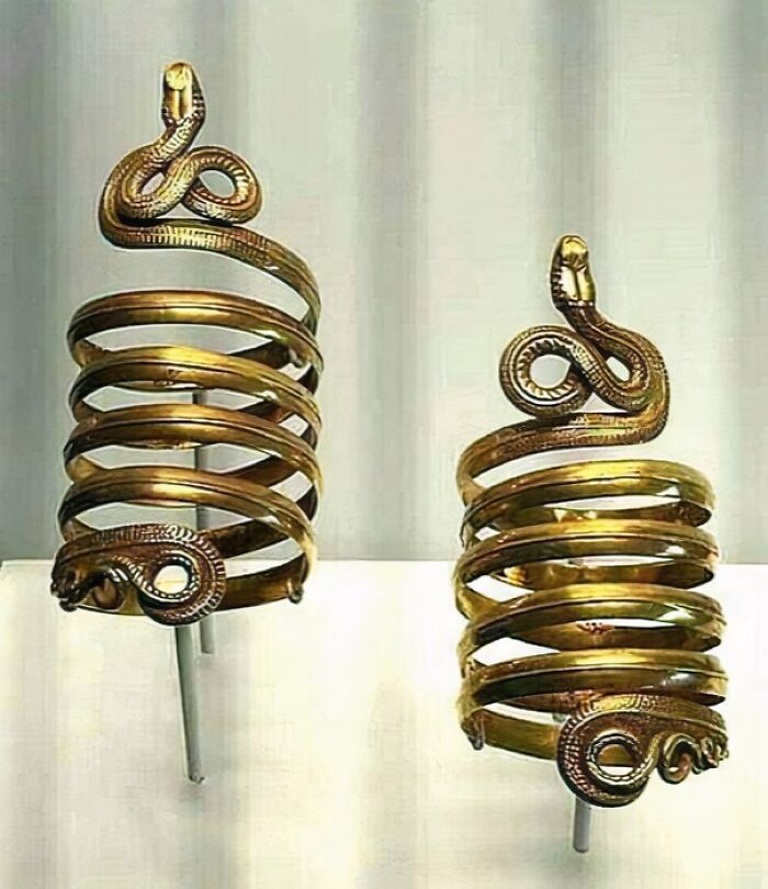 Ancient gold spiral arm bracelets with snake designs, notable archeology finds from around the world displayed in a museum.