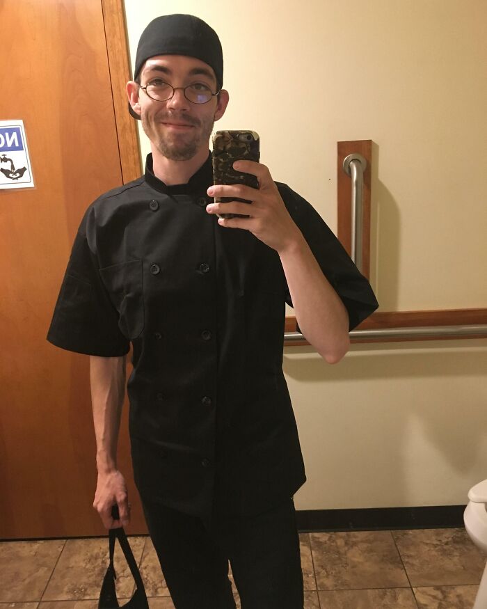 Young man in black chef uniform taking a mirror selfie showing the realization of big and small dreams.