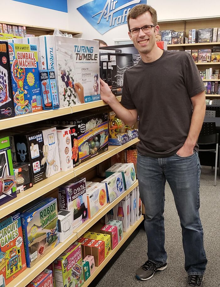 Man smiling in a game store showing off creative toys and inspiring big and small dreams turned into reality.