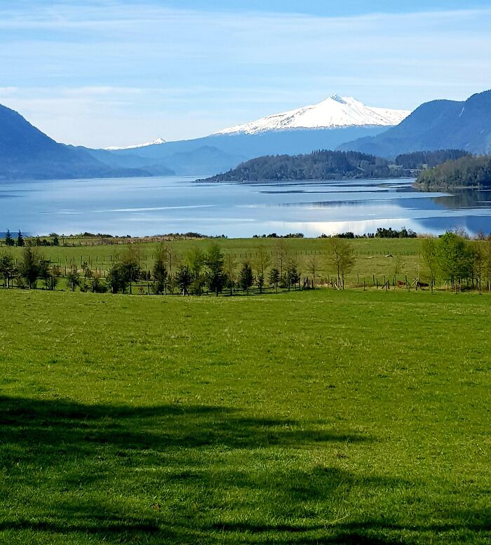 Scenic landscape with green fields, distant snow-capped mountains, and a calm lake inspiring dreams turned into reality.