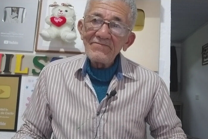 Elderly man wearing glasses and striped shirt speaking in a video capturing viral moments of internet icons.