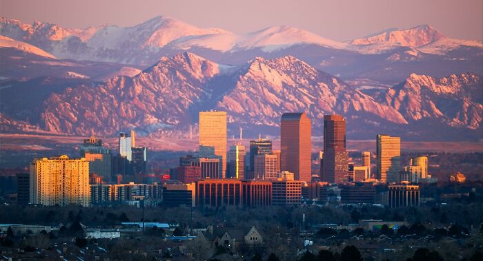 City skyline at sunset with mountain backdrop, illustrating Miami among 38 cities that do not live up to their online hype.