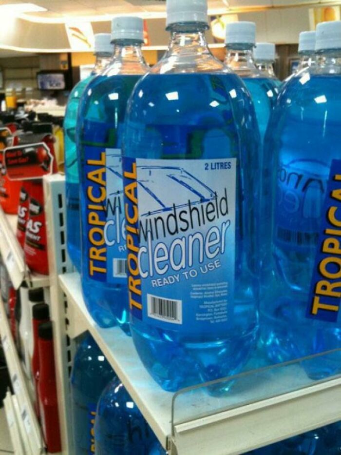 Bottles of blue windshield cleaner on store shelves representing forbidden foods to avoid for safety.