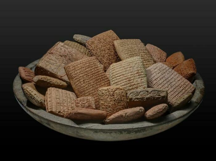 Ancient clay tablets with cuneiform inscriptions displayed on a dish, illustrating forbidden foods theme.