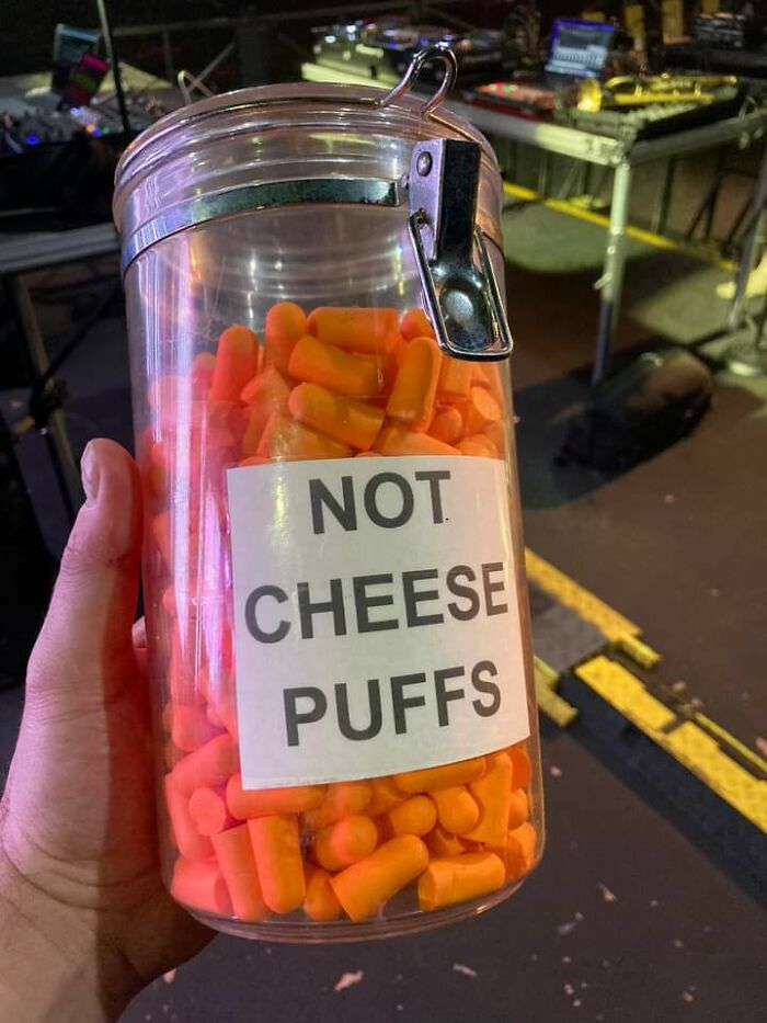 Hand holding a jar filled with orange earplugs labeled not cheese puffs illustrating forbidden foods to avoid.