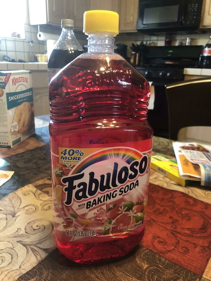 Bottle of red Fabuloso cleaner with baking soda on kitchen table, example of forbidden foods to avoid consuming.