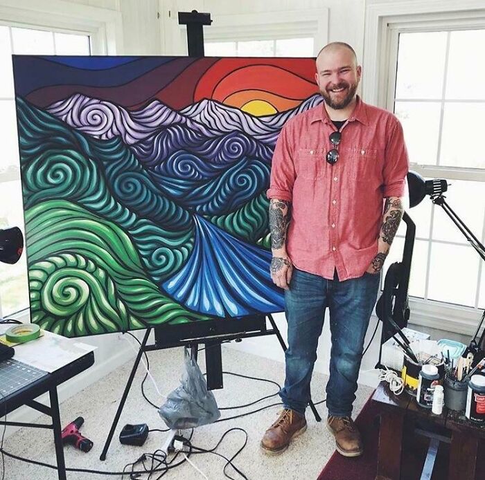 Artist standing beside vibrant painting of swirling mountains and river, turning big and small dreams into reality.
