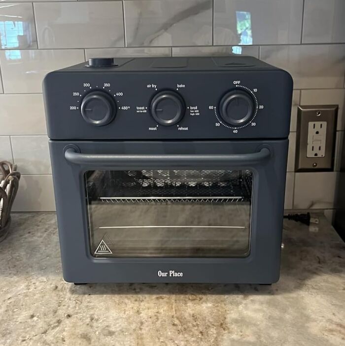 Compact black air fryer oven on kitchen countertop featuring multiple cooking settings and temperature controls for Black Friday kitchen deals.
