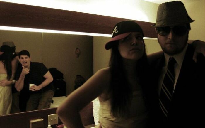 Two people posing seriously while a photobomber makes a funny face in the background, capturing an epic photobomb moment.