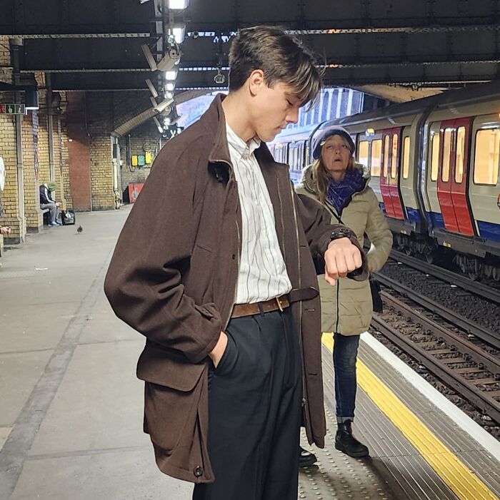 Young man checking watch at train station while a photobomb behind steals the show in this epic photobomb moment.