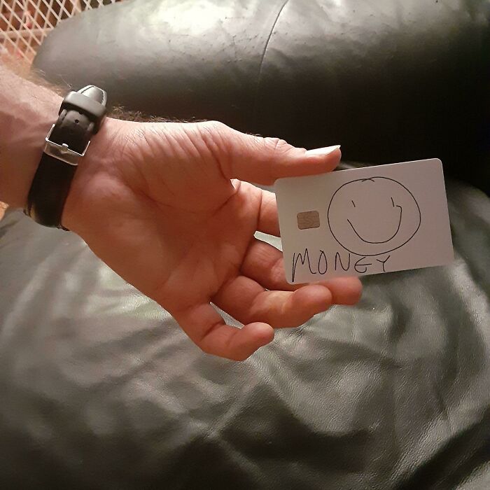 Man's hand holding a playful card with a smiley and the word money, showcasing wholesome humor in men never growing up.