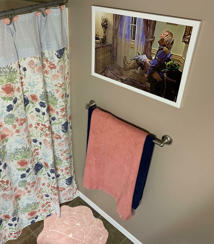 Bathroom with colorful floral shower curtain, towels, and framed wholesome photo showing men never grow up theme.