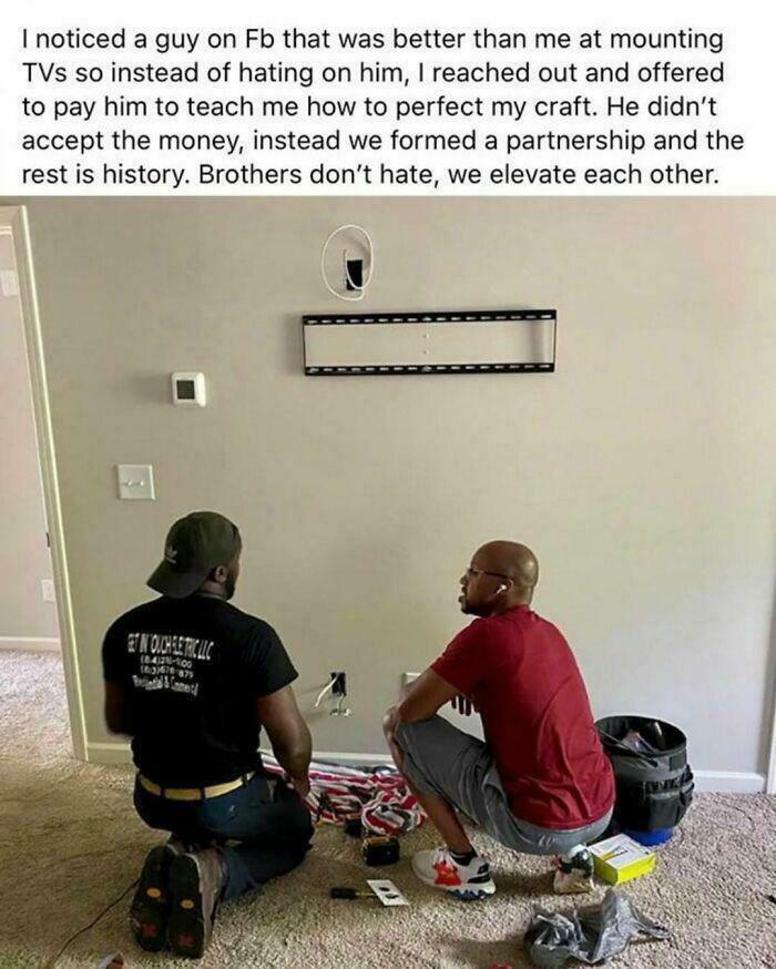 Two men collaborating to mount a TV, showcasing wholesome internet moments of kindness and partnership.