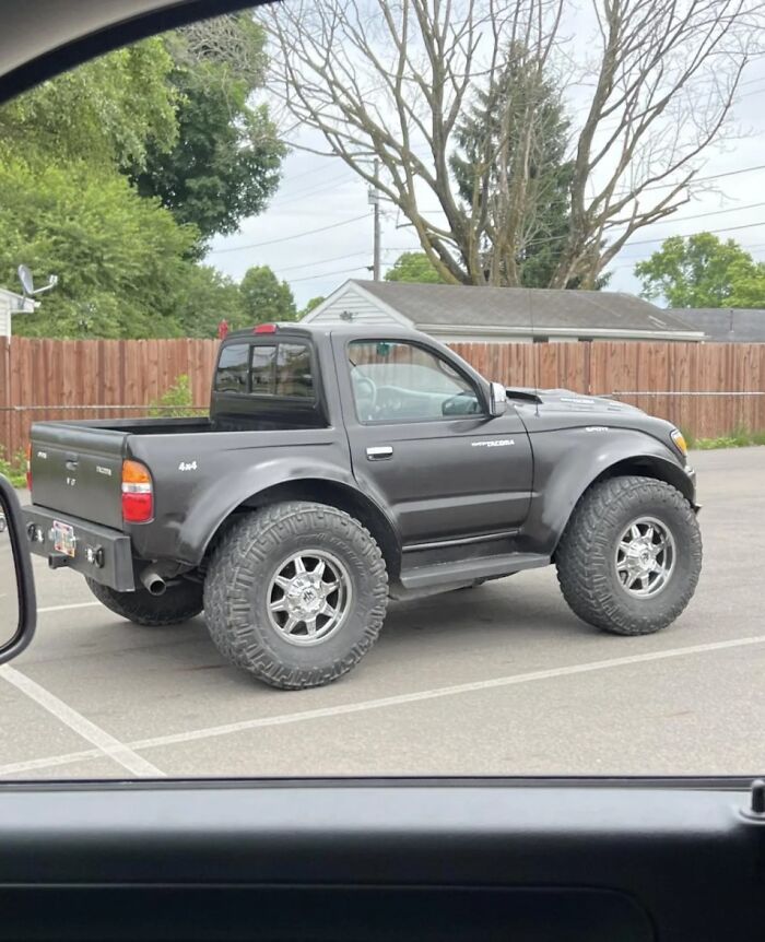 Modified truck with oversized off-road tires parked in lot, example of people trying to make their cars cooler but failing.