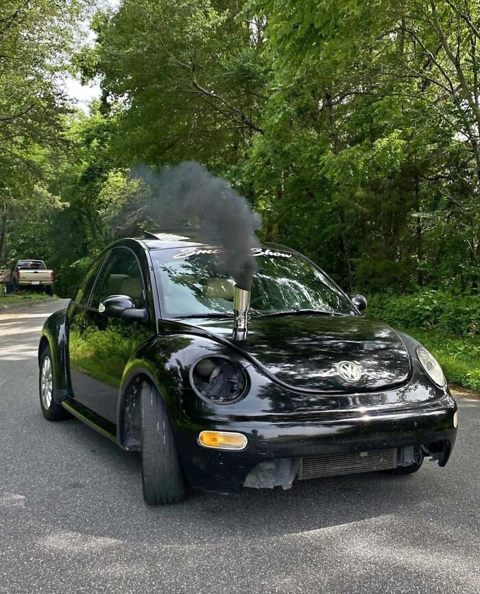 Black Volkswagen Beetle with a large exhaust pipe on the hood emitting thick black smoke, demonstrating stupidity on wheels.