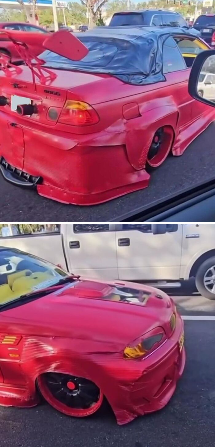 Red car with heavily damaged custom body kit and spoiler, an example of stupidity on wheels trying to look cooler.