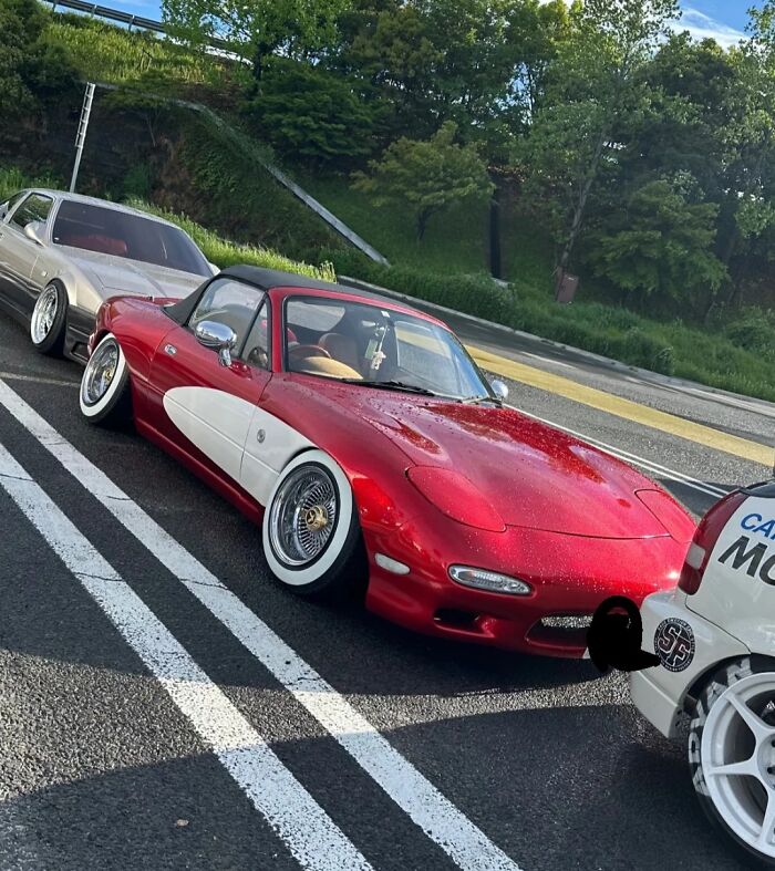 Red car with unusual white side panel and lowered wheels shows an example of stupidity on wheels in car modifications.