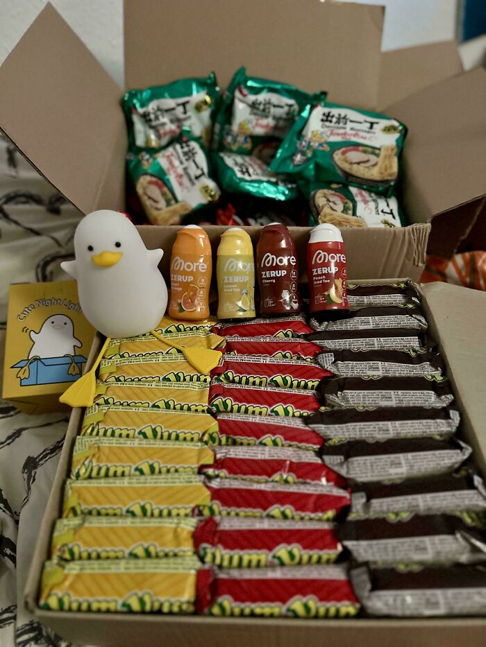 Box filled with snacks and a cute duck night light representing wholesome internet moments and positive online world vibes.