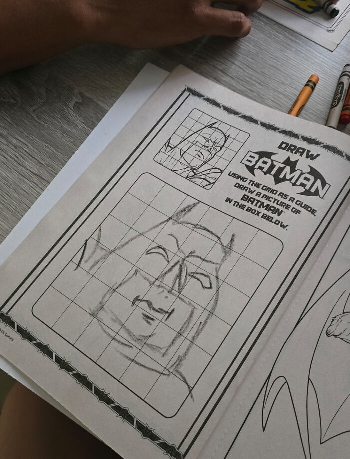 Hand drawing a Batman sketch using a grid guide, illustrating wholesome photos proving men never grow up.