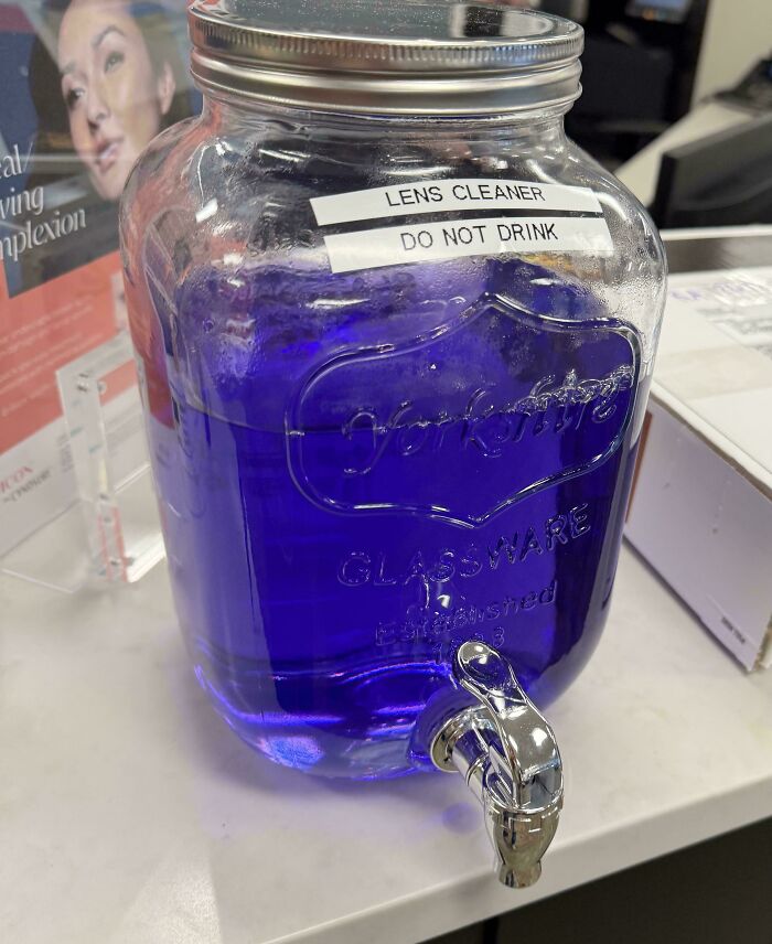 Large glass container with purple lens cleaner labeled do not drink, illustrating forbidden foods to avoid for safety.