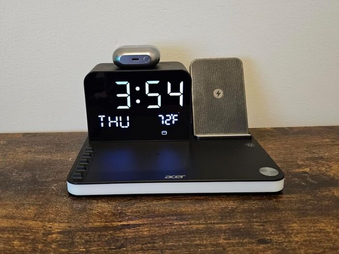 Acer digital clock with wireless charging station holding earbuds and phone, showcasing Black Friday tech deals.