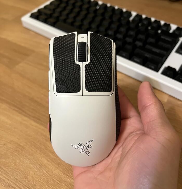 White gaming mouse with textured buttons held in hand, keyboard in the background, highlighting Black Friday tech deals.