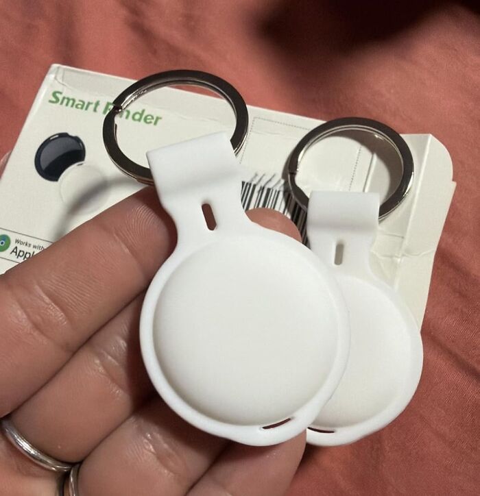 White smart finder keychains with metal rings held over packaging for Black Friday tech deals.