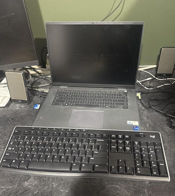 Laptop with wireless keyboard and speakers on a cluttered desk showcasing Black Friday tech deals for tech enthusiasts