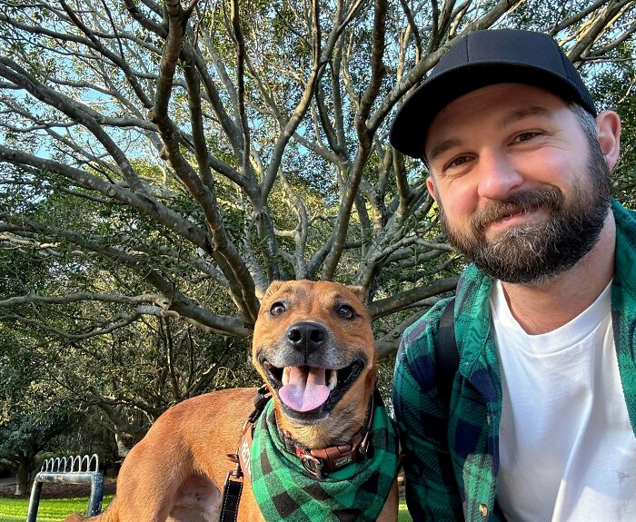 Man and his happy dog wearing matching green plaid outdoors showing dogs make our lives better.