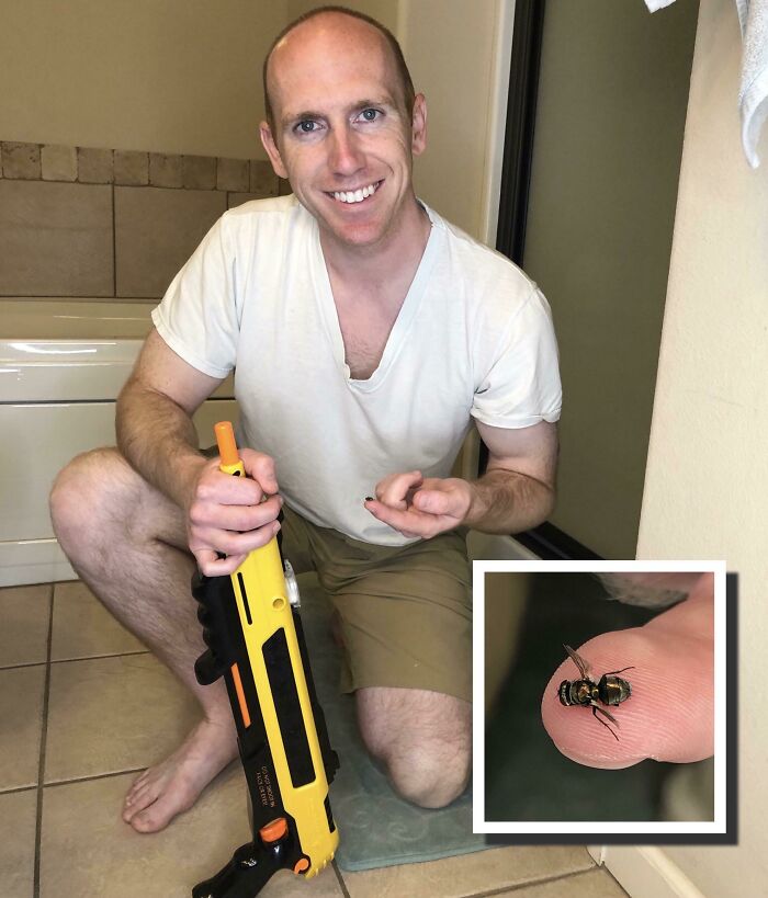 Man smiling and holding toy gun while showing a small captured insect, highlighting men never grow up in a wholesome moment.