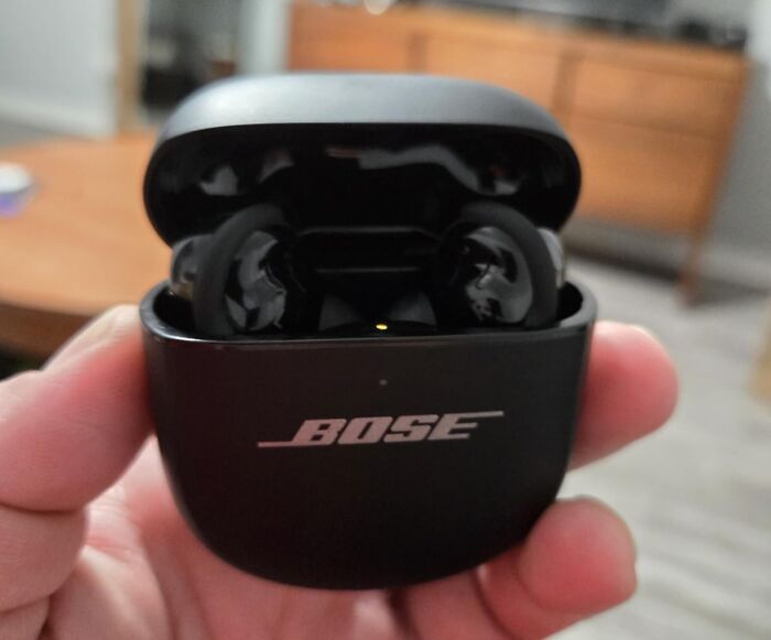 Close-up of black Bose wireless earbuds in charging case held in hand from Alix Earle’s Amazon Black Friday deals.