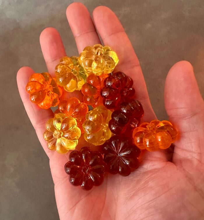 Hand holding colorful gummy candies shaped like flowers representing forbidden foods to resist for your health.