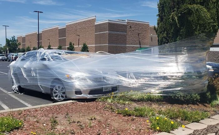 Car wrapped entirely in plastic wrap as part of employee prank, showcasing jokes and pranks with zero regrets.
